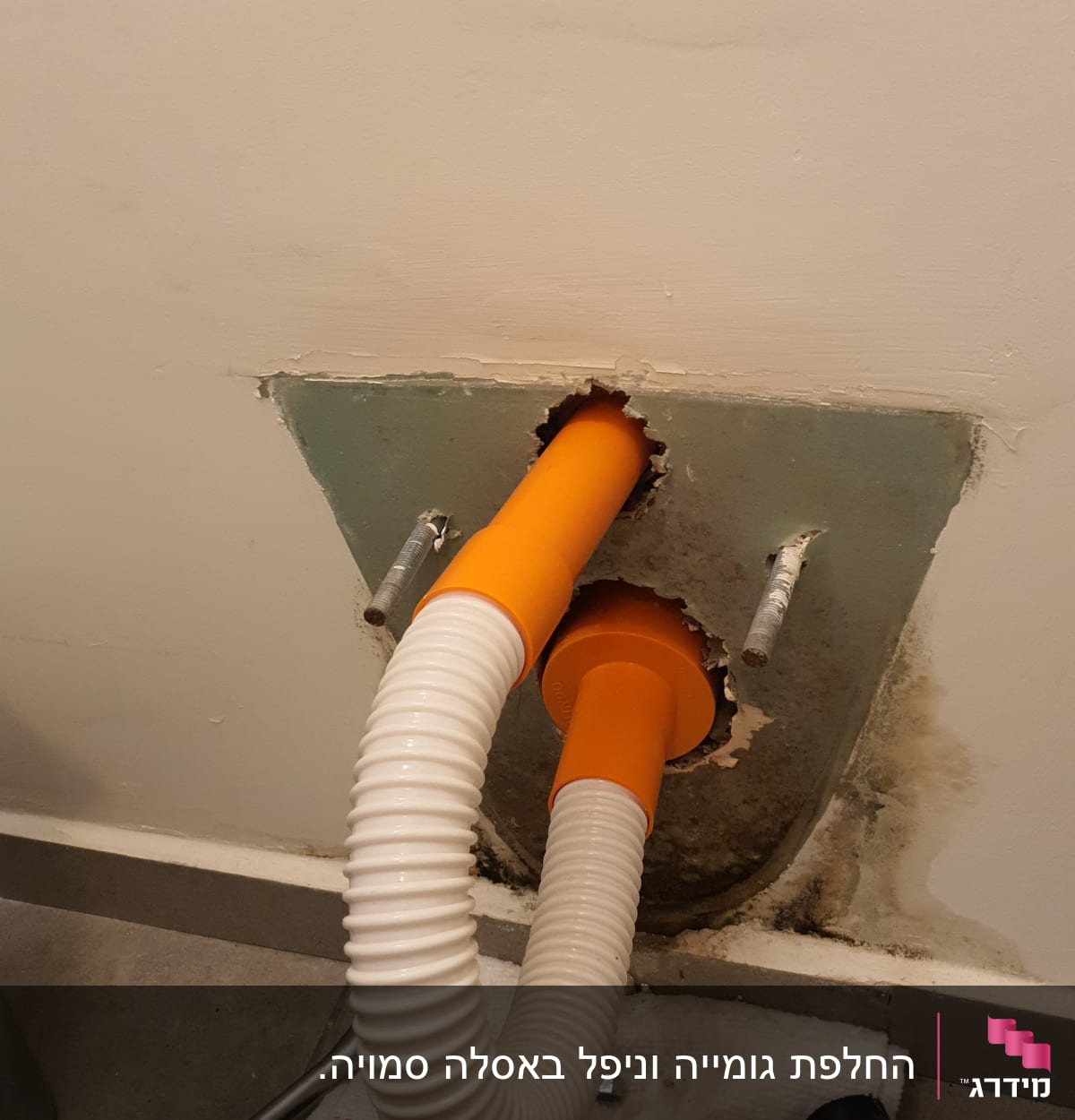 צינור כתום ולבן מחובר לקיר עם כלים